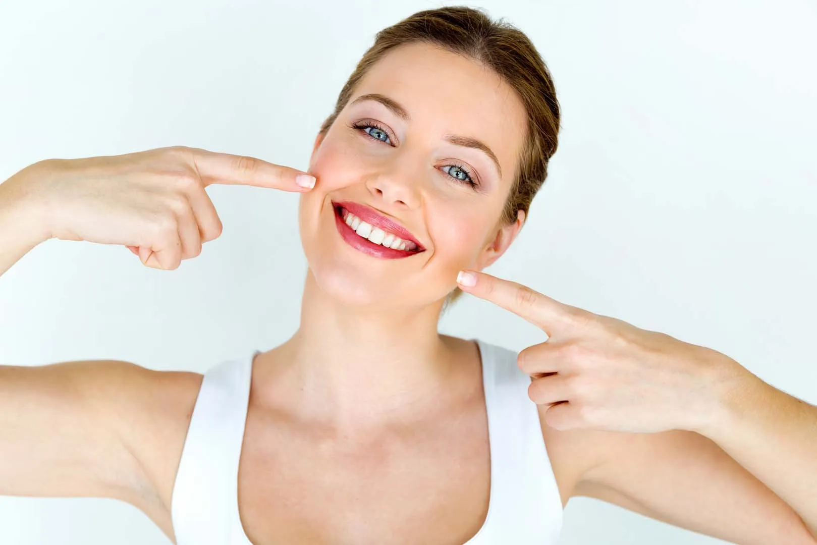Smiling woman pointing to her new smile after a smile makeover in Newkirk, OK